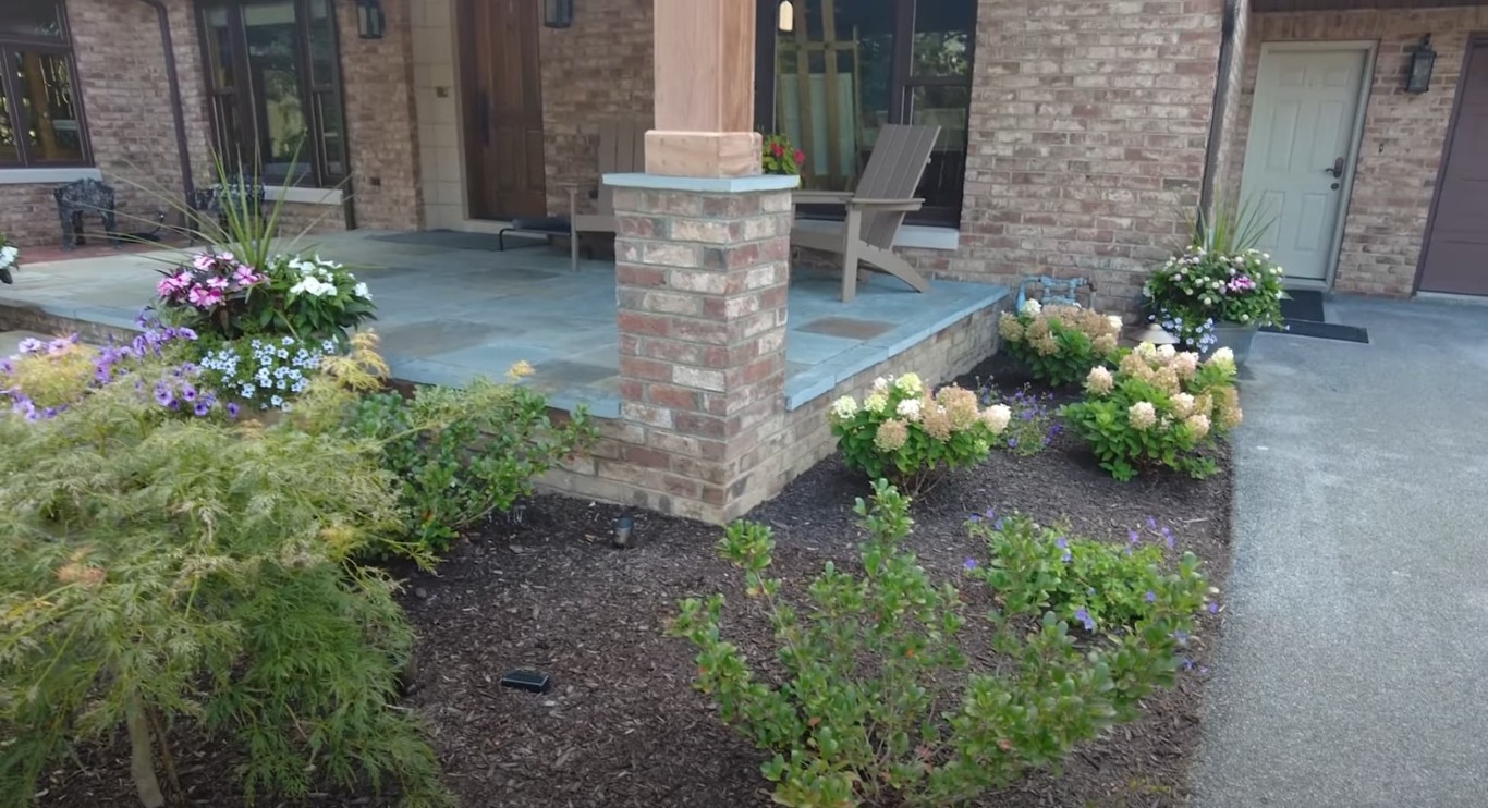 Patio hardscaping with bluestone paving and flowering plants in Irondequoit, NY